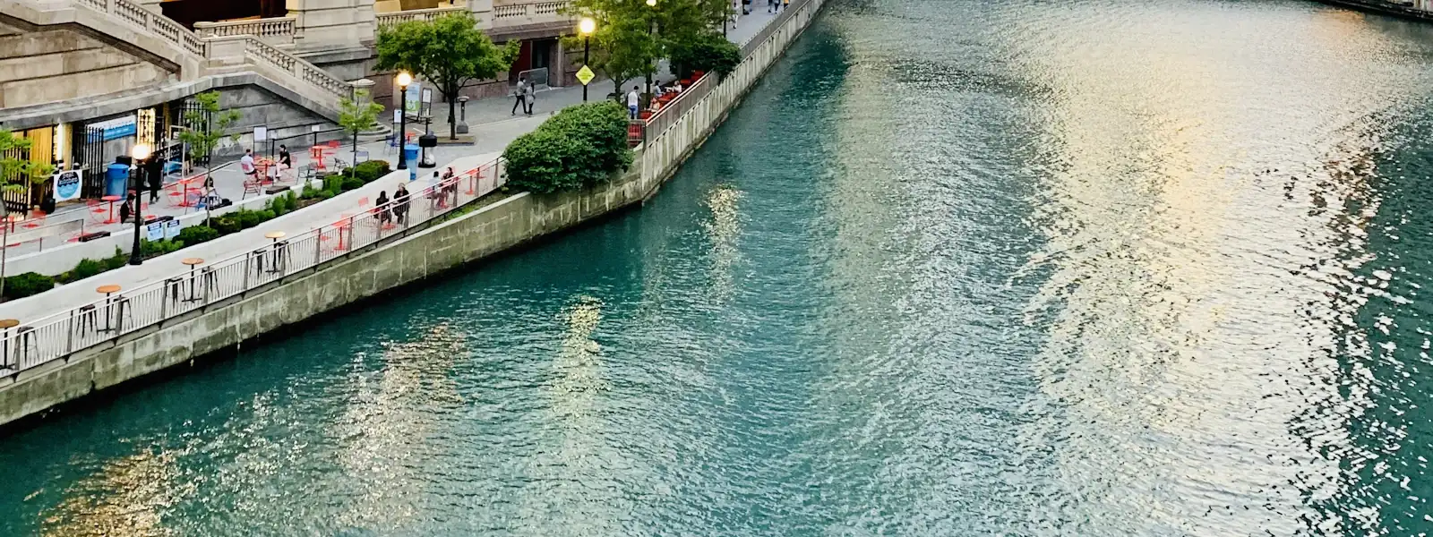The Chicago Riverwalk at dusk with the bridges lit overhead
