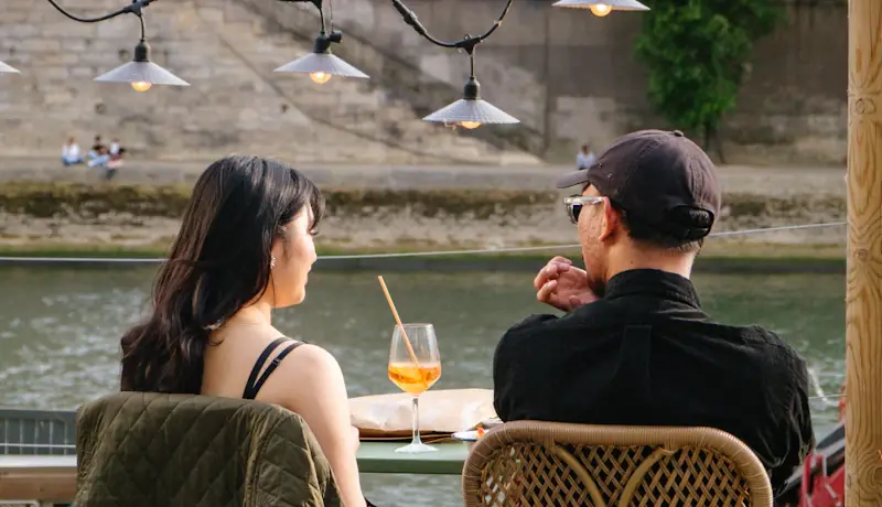 Two people talking at a riverside cafe table